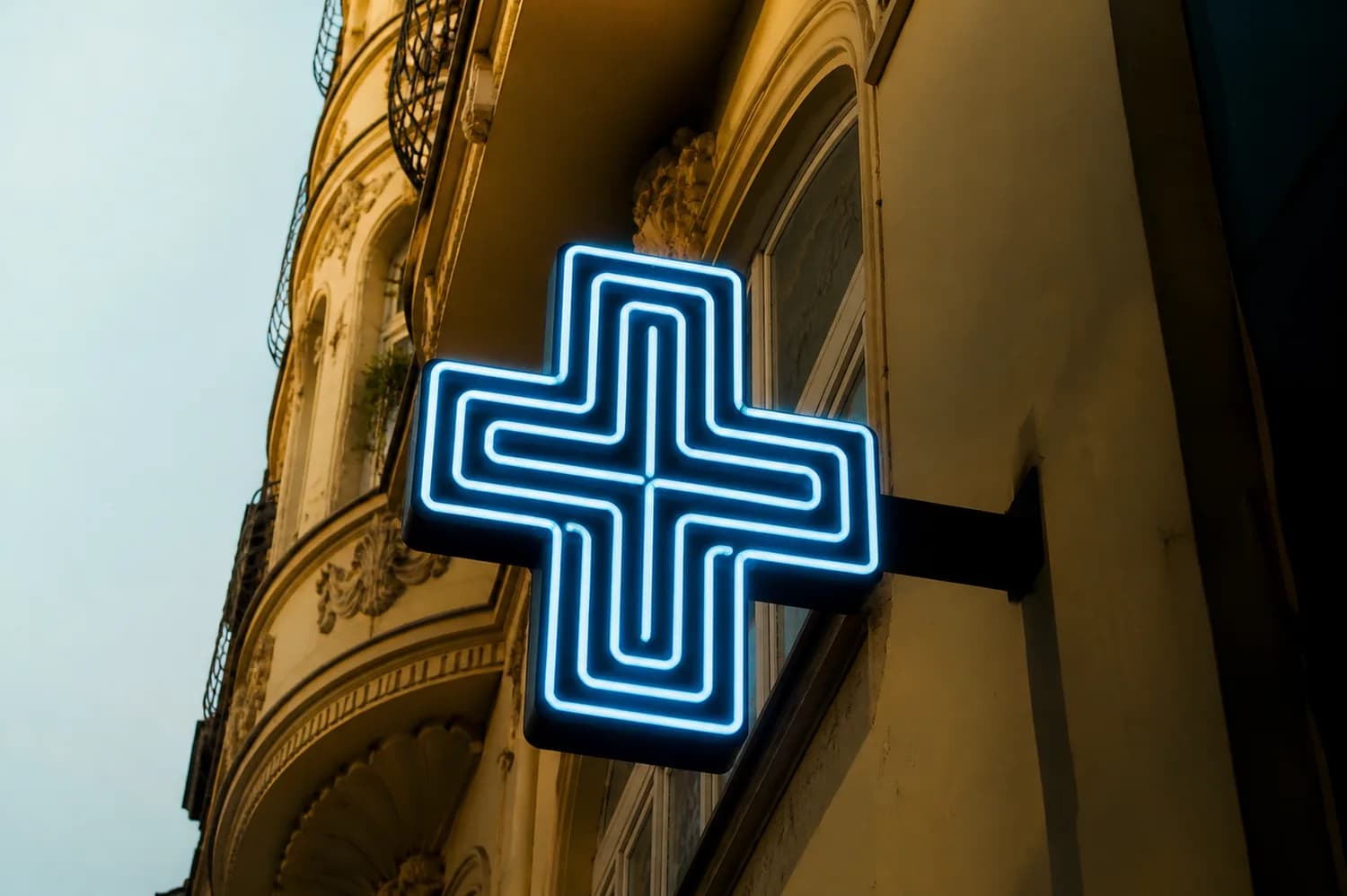 Leuchtendes Apotheken-Kreuz an einer Hausfassade